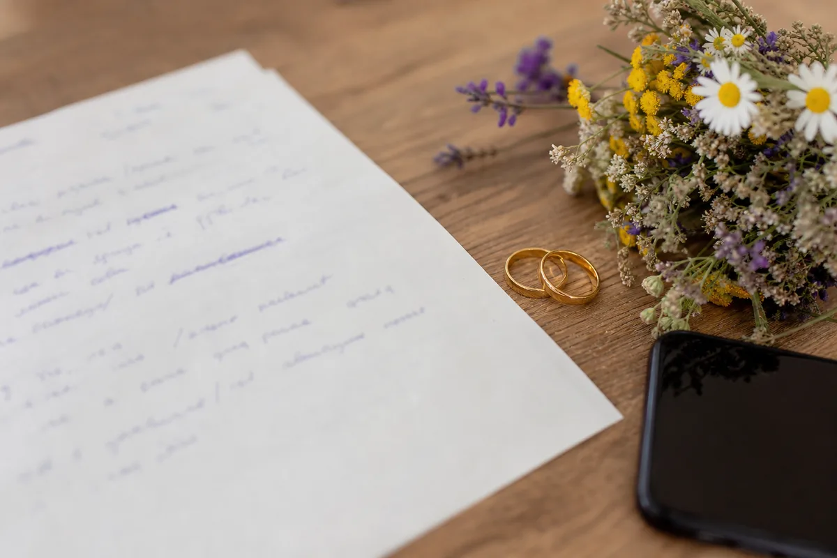 Feuille de route manuscrite du jour J posée près d&rsquo;un bouquet et de deux alliances